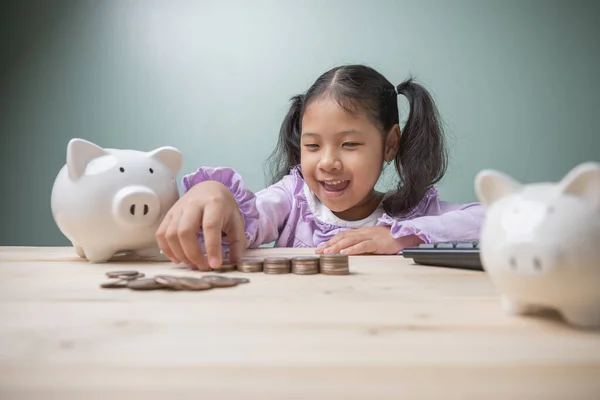 Concept to save money for education. Cute Asian kid girl smile happiness is counting money for saving money to the future. Ideas savings money for tuition fees, the cost of school supplies.