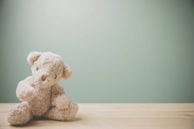 Eski ahşap bir masada oturan tek bir kahverengi oyuncak ayı üzgün bir şekilde fotokopi aletiyle doludur. Bu sevimli pofuduk bebek çocuklar için mükemmel. Çocukların oynaması için bir hediye olarak. Klasik resim biçimi.