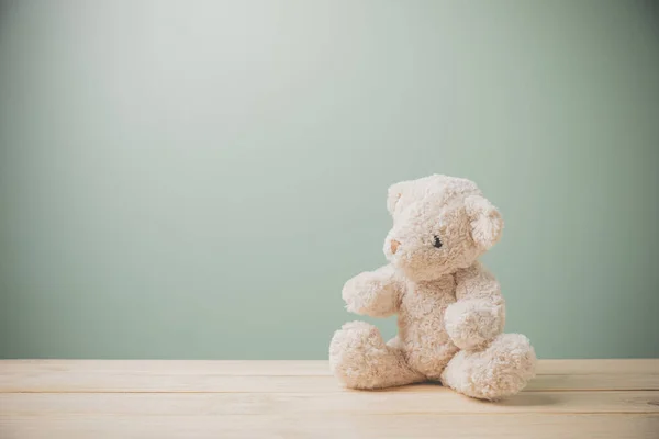 Eski ahşap bir masada oturan tek bir kahverengi oyuncak ayı üzgün bir şekilde fotokopi aletiyle doludur. Bu sevimli pofuduk bebek çocuklar için mükemmel. Çocukların oynaması için bir hediye olarak. Klasik resim biçimi.