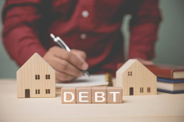 Debt Blocos Madeira Com Modelo Casas Empresário Segurando Uma Caneta — Fotografia de Stock