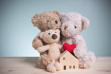 Konsept bankacılık, kredi, tasarruf. Baba, anne ve ahşap ev modelleri olan küçük ayılar eski ahşap masa üzerinde fotokopi alanı olan. Geleceğe yönelik bir aile için ev almak için tasarruf parası planlamak..