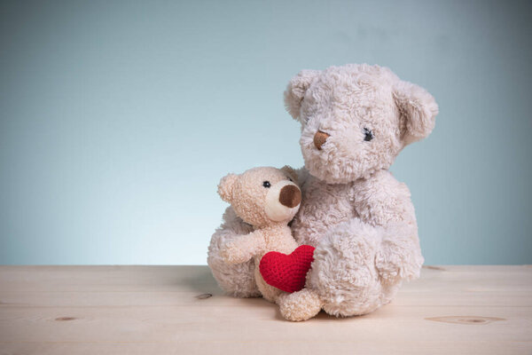 Big and little brown teddy bears sitting huggy show love, happiness on an old wooden table with copy space. Concept family, love, and valentines festival.