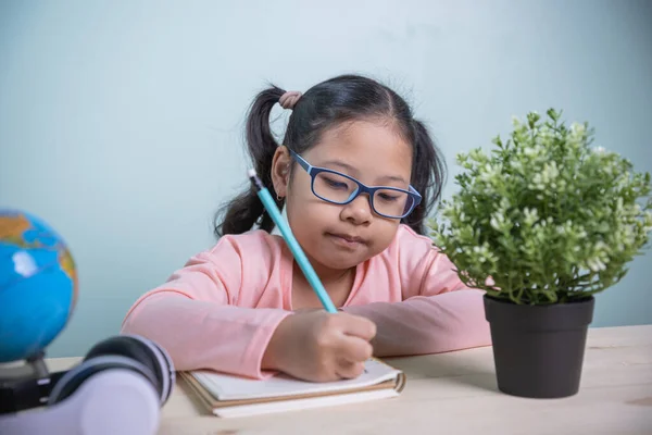 戴眼镜的亚洲学生女孩开心地笑着在笔记本上写着从家里学到的东西 从家庭社会距离进行在线概念学习 — 图库照片