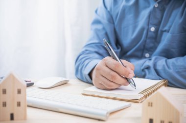 İş adamları harcamaları kaydetmek için kalemleri kullanırlar. Gayrimenkul yatırımları ve bankadan gelecek için ev almak için kredi. Sigorta, kredi, finans ve bankacılık yatırım kavramı.