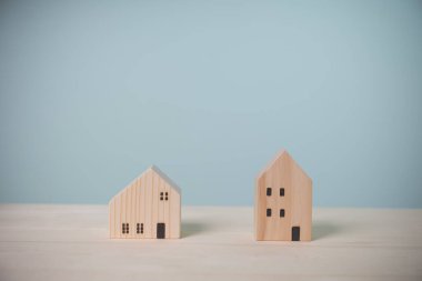 Mini ahşap ev. Eski ahşap bir masada iki model. Yatırım şirketinden gelecek kar için gelir elde ediyoruz. Sigorta, kredi, finans ve bankacılık yatırım kavramı.