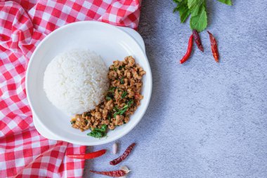 Geleneksel Tayland yemeğinin üst manzarası, taze, canlı malzemeler sergileniyor: kıyma, yeşil fesleğen yaprağı ve beyaz pirinç yatağının üzerinde servis edilen kırmızı biber. Kopyalama alanı olan arkaplan.
