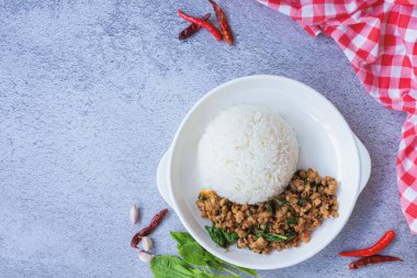 Geleneksel Tayland yemeğinin üst manzarası, taze, canlı malzemeler sergileniyor: kıyma, yeşil fesleğen yaprağı ve beyaz pirinç yatağının üzerinde servis edilen kırmızı biber. Kopyalama alanı olan arkaplan.