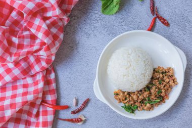Geleneksel Tayland yemeğinin üst manzarası, taze, canlı malzemeler sergileniyor: kıyma, yeşil fesleğen yaprağı ve beyaz pirinç yatağının üzerinde servis edilen kırmızı biber. Kopyalama alanı olan arkaplan.