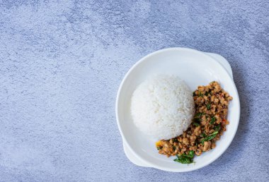 Baharatlı fesleğenli domuz eti ve buğulanmış pilavın üst görüntüsü Tayland 'ın otantik bir tadını gösteren sıcak ve bitkisel tazeliğin enfes bir karşıtlığını sunar. Kopyalama alanı olan arkaplan.