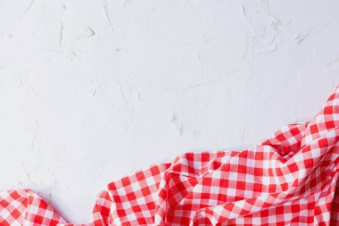 Beyaz Çimento yüzeyinde kırmızı ve beyaz pamuklu kumaş. Kırmızı gingham ve beyaz çimento arka plan. Dokulardaki kontrast, çimento kumaş, kırmızı ve beyaz pamuk kumaş, kopya alanı ile.