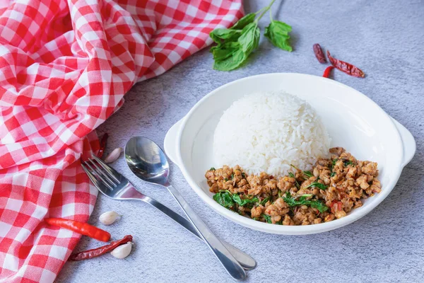 Kopya alanı olan bir arkaplan. Geleneksel bir Tayland yemeği, taze, canlı malzemeler sergileniyor: kıyma, yeşil fesleğen yaprağı ve beyaz pirinç yatağının üzerinde servis edilen kırmızı biber..