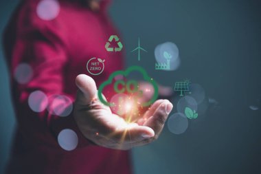 Ağ Sıfır Simgeleri ile Yeşil Karbondioksit Azaltma Kavramının Eli. Karbondioksit salınımını ve net sıfır ikonlarını temsil eden yeşil bir grafik üzerinde yüzen, uzanmış eli olan bir iş adamı..