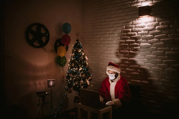 Święty Mikołaj Kapeluszu Masce Twarzy Siedzi Przed Laptopem Rozmawia Przez — Zdjęcie stockowe