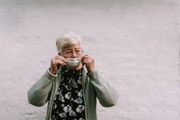 Mujer Mayor Caucásica Con Gafas Pone Mascarilla Frente Pared Blanca —  Fotos de Stock