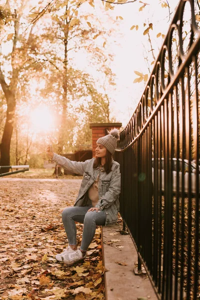 청바지를 도시의 소녀가 울타리에 전화로 셀카를 공원의 — 스톡 사진