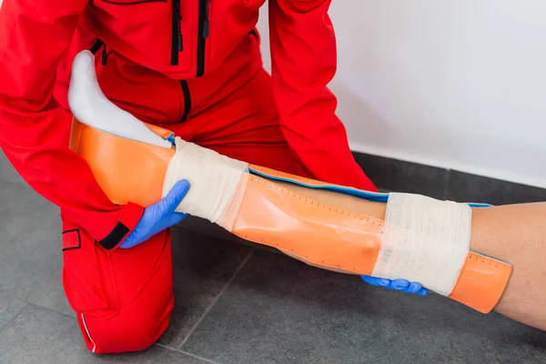 Bacağı sakat. Bacağı yaralı genç bir adam. Genç kadın doktor hastaya yardım eder. Yakın çekim. İlk yardım