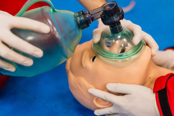 Doktor, bir hastanenin ameliyathanesinde tıbbi hasta simülatörü kullanarak oksijen maskesi kullandığını gösteriyor.