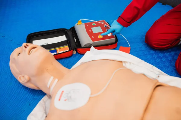 Kalp masajı ve eğitim. Paramedikler dumm üzerinde kardiyopulmoner resüsitasyon (kalp masajı) gösteriyor ve parmağını aparatta tutuyor.