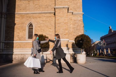 Parkta iki güzel genç kadın ellerinde çantalarla poz veriyorlar. Sonbahar alışverişi
