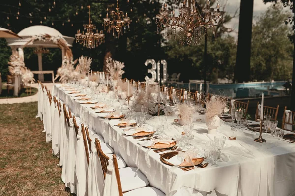 日没の庭で美しい結婚式のイベント 祭りのテーブルは料理を提供し 緑の枝で飾られ 結婚式のパーティーのエリアの緑の芝生の上に立つ — ストック写真