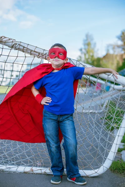 Superheld lehnt sich an Fußballtor an — Stockfoto