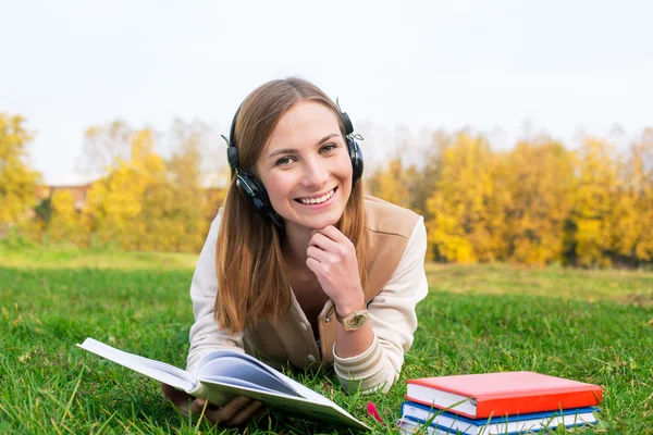 Student hoofdtelefoon beluisteren en lezen van boek — Stockfoto