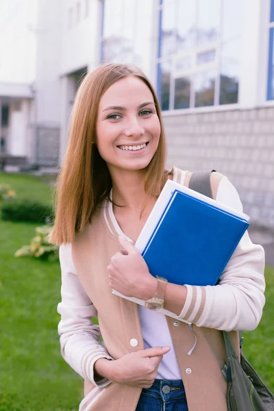 Studentin steht mit Buch in der Hand und lacht — Stockfoto