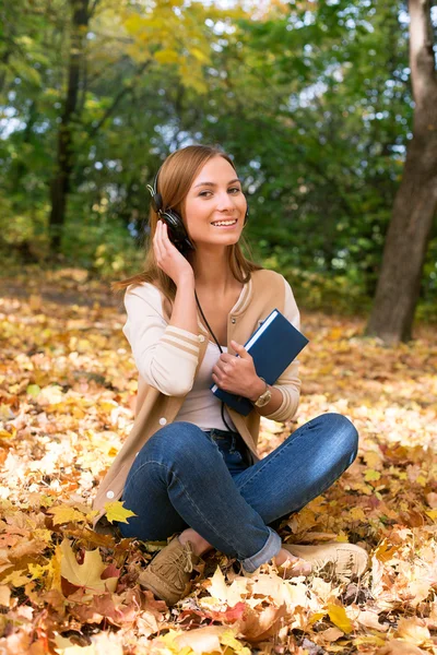 Siswa duduk dengan headphone di antara daun maple — Stok Foto