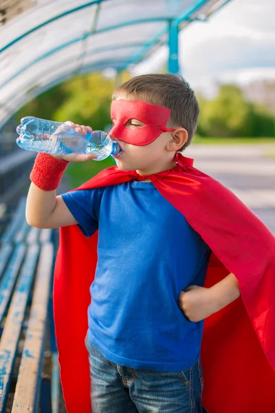 Superhero standing and drinking water from a bottle — Stock Photo, Image