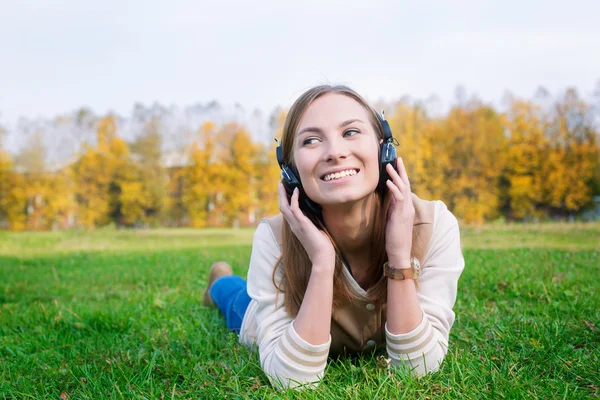 Estudante ouvindo fones de ouvido e olhando para — Fotografia de Stock