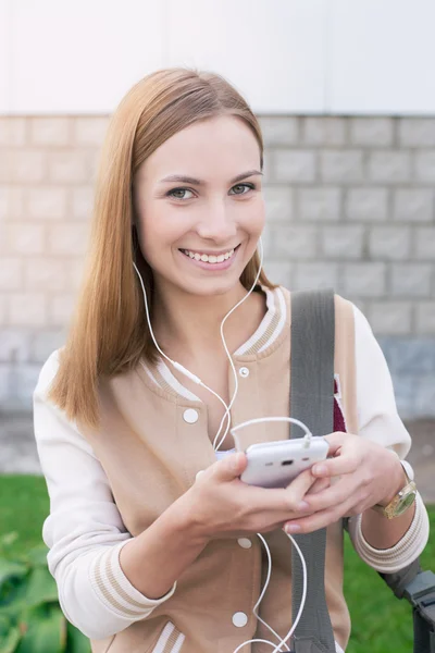 Student hört Kopfhörer und hält Handy — Stockfoto