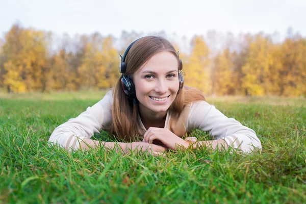 Student hört Kopfhörer und liegt auf grünem Gras — Stockfoto