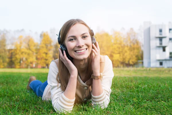 Student listening to headphones and smiling at camera — Stock Photo, Image