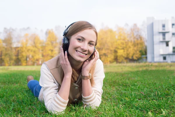 Student liegt auf grünem Gras und hört Kopfhörer — Stockfoto