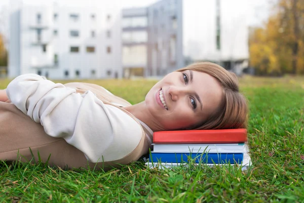 Student liggen op groen gras en boeken — Stockfoto