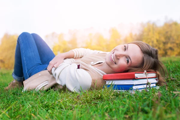 Student lying on green grass and books and looking up — Stock Photo, Image