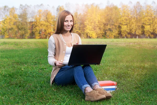 Student sitter på grönt gräs med öppnade notebook ligger på den — Stockfoto