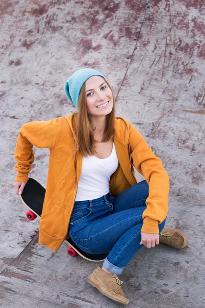 Student sitting on skateboard and smiling at the camera — Stock Photo, Image