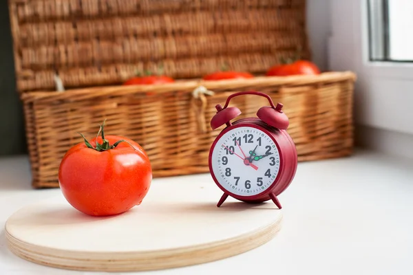 Eine Tomate und eine rote Uhr — Stockfoto