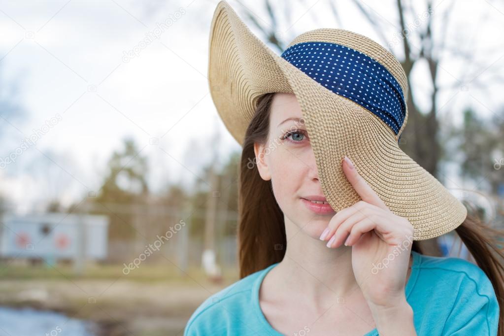 Freckled girl covering one eye by hat