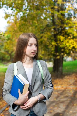 Student with book standing in autumn