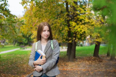 Student standing with book in autumn