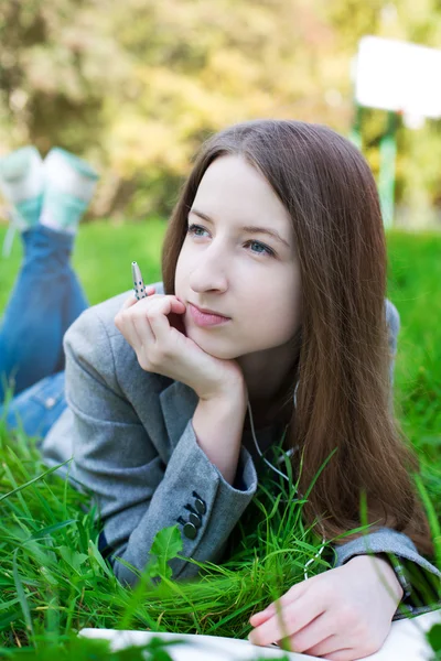 Student with pen thinking on grass — Stockfoto