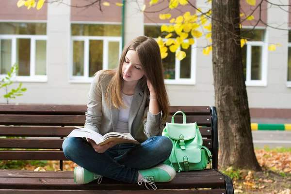 Student reading book in autumn — Zdjęcie stockowe