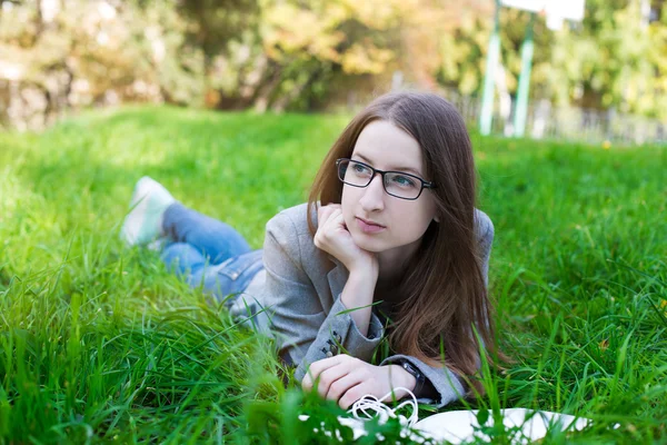 Student with glasses lying on grass — Stockfoto