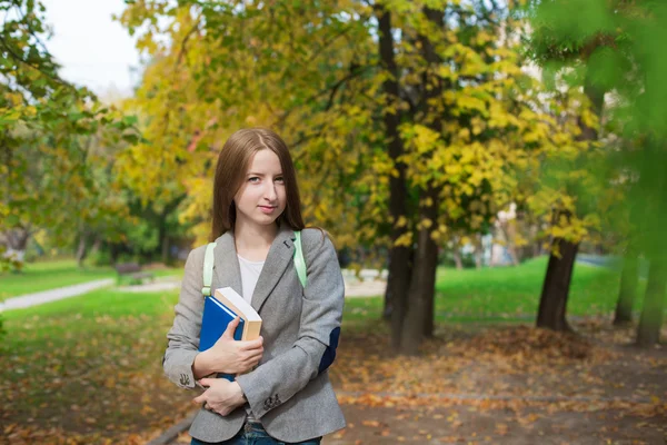 Studentin steht mit Buch im Herbst — Stockfoto