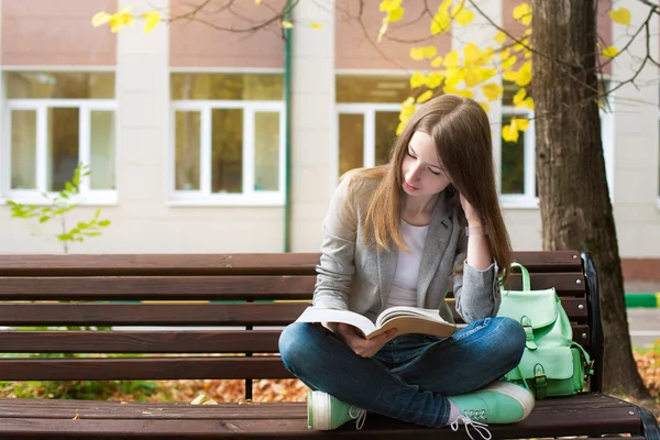 Studentin liest Buch auf Bank — Stockfoto