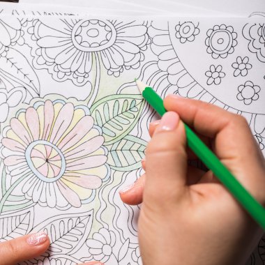 Kız boya kalemi ile yetişkinler için bir boyama kitabı boyalar