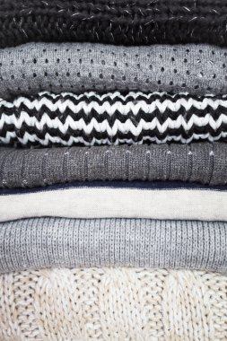 Beyaz ahşap zemin üzerinde çeşitli yün kazak yığını