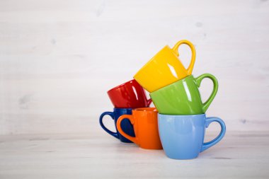 Beyaz ahşap arka plan üzerinde renkli kahve fincanı yığını